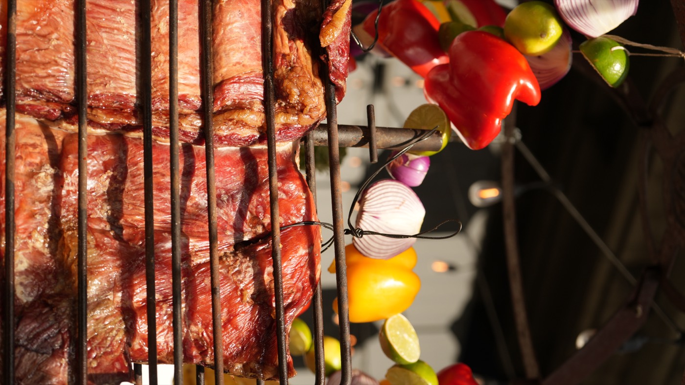 Fire-roasted peppers and vegetables beside the asado